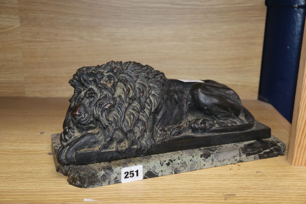 After Canova, a bronze recumbent lion, on a marble plinth, length 35.5cm